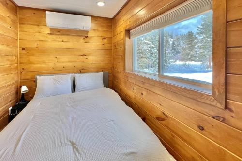 冬季公園的住宿－Camp Contained，木制客房的一张床位,设有窗户