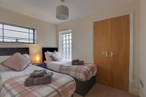 a bedroom with two beds and a door with a window at Niche Water Tower Apartments in Braintree