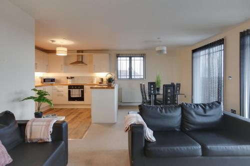 a living room with a black couch and a kitchen at Niche Water Tower Apartments in Braintree