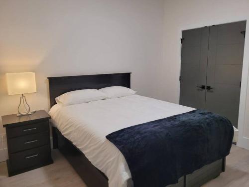 a bedroom with a large bed and a nightstand with a lamp at Spacious getaway for couples with separate entrance in Surrey