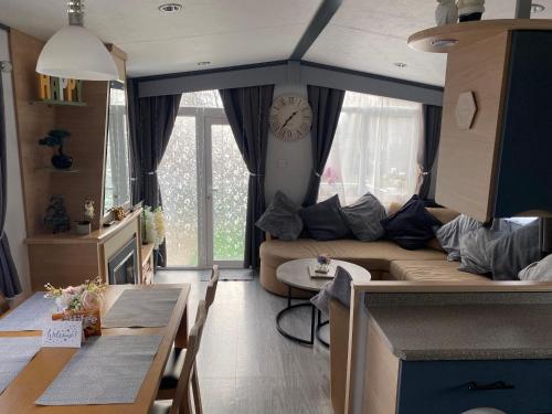 ein Wohnzimmer mit einem Sofa und einer Uhr an der Wand in der Unterkunft Luxury Holiday Home Happiness at Tattershall lake# in Tattershall