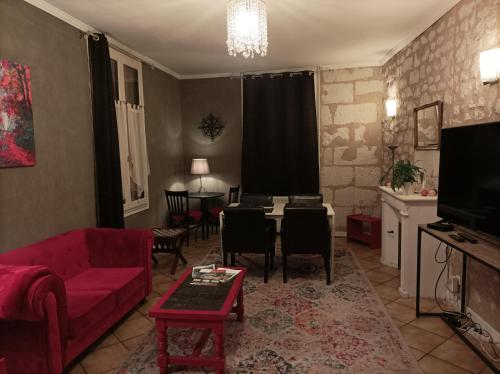un soggiorno con divano rosso e tavolo di La Boussole - Maison meublée 3 chambres 6 pers. a Chinon