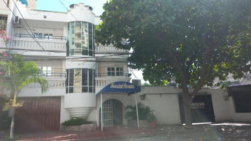 un edificio blanco con un árbol delante en HOSTAL PARMA, en Santa Marta