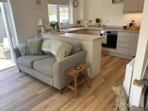 a living room with a couch and a kitchen at Lotties Cottage in Broadway