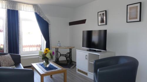 a living room with a couch and a tv at Pension Zur Mühle in Fredersdorf