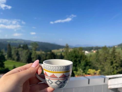 a person holding a coffee cup with a view at Attico con vista AltopianoAsiago in Roana