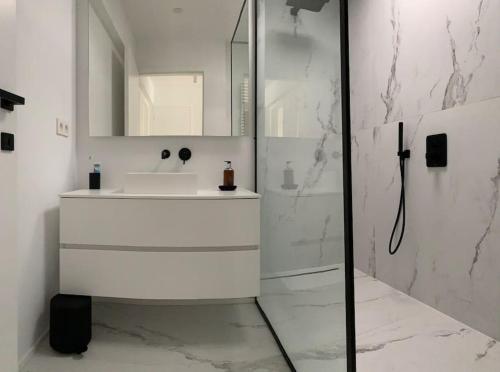 La salle de bains blanche est pourvue d'un lavabo et d'une douche. dans l'établissement Beautiful penthouse at 5min of Albert place, à Knokke-Heist
