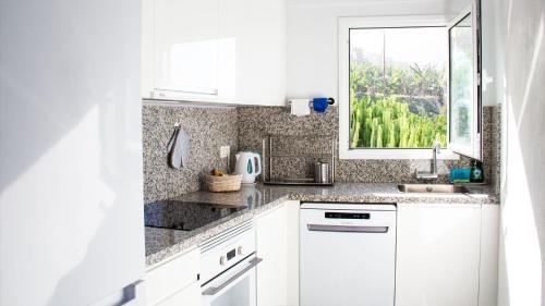 una cocina con armarios blancos y una ventana en Casa Sol y Mar en Garachico