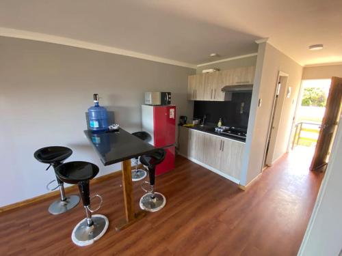 a kitchen with a table and two bar stools at Departamento N con hermosa vista al mar in Los Vilos