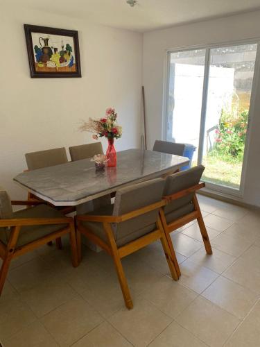 una mesa de comedor con sillas y un jarrón con flores en Borrallas, en Puebla