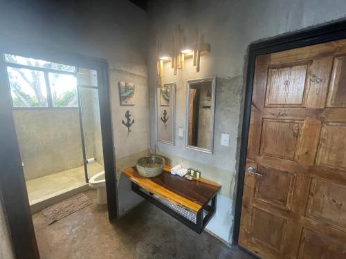 a bathroom with a sink and a toilet and a door at San Carlos Surf Resort & Eco Lodge in San Carlos