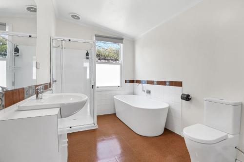 a bathroom with a tub and a sink and a toilet at Avery Cottage in Port Fairy