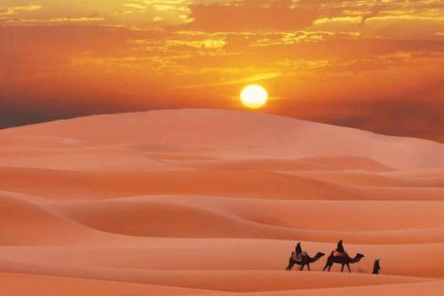 two people riding horses in the desert at sunset at Camp Golden Desert Morocco in Mhamid
