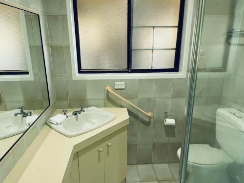 ein Bad mit einem Waschbecken, einem WC und einem Fenster in der Unterkunft Peaceful 2 Bedroom Home in Wagga Wagga