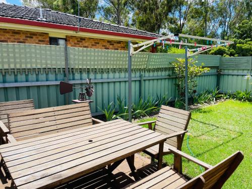 two wooden benches in a yard with a fence at Peaceful 2 Bedroom Home in Wagga Wagga