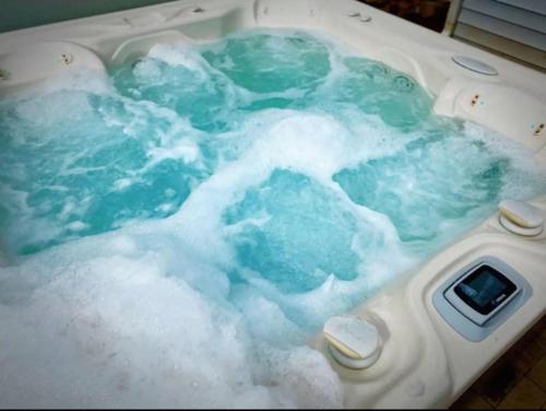 Stylish 4B 3B -King Bed- Jacuzzi في تشارلوت: حوض الاستحمام مملوء بالماء الأزرق مع الرغوة