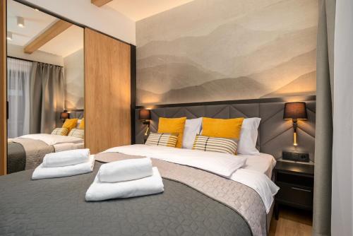 a bedroom with two beds with yellow and white pillows at REST4U APARTAMENTY z SAUNAMI in Szczyrk
