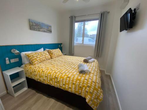 a bedroom with a bed with yellow sheets and a window at Woolacombe Breaks - ‘Sea La Vie’ in Woolacombe