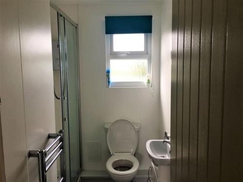 Un baño con inodoro, lavabo y ventana. en Woolacombe Breaks - ‘Sea La Vie’, en Woolacombe