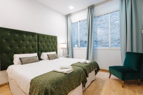a bedroom with a large bed and a green headboard at HomeySeville-Amazing Views Cathedral Tomas de Ibarra - 8 pax, Parking Optional in Seville