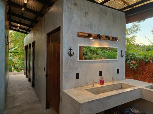 a concrete bathroom with a sink and a window at Shipwrecked Hostel in Uvita