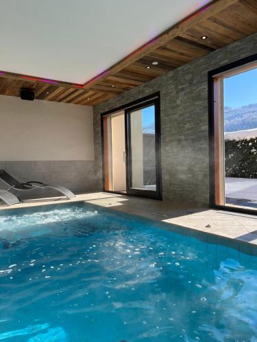 una piscina de agua azul en una habitación con ventanas en GITE BALNEO LES AMARYLLIS, en Taninges