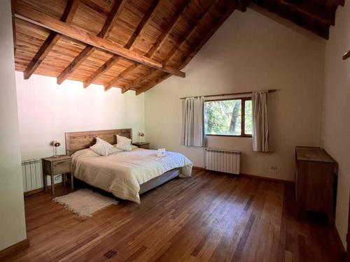 1 dormitorio con 1 cama y suelo de madera en Casa en San Martin de Los Andes en San Martín de los Andes