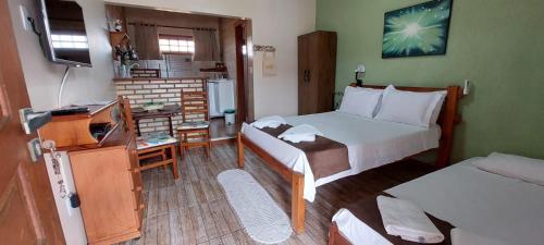 a small room with a bedroom with a bed and a desk at Estúdio Recanto Dos Anjos in Arraial do Cabo