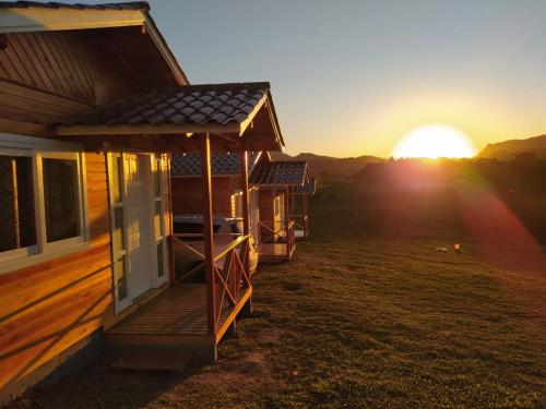 a wooden cabin with the sunset in the background at Pousada Flor do Campestre in Urubici