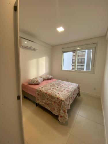 a small bedroom with a bed and a window at Apartamento em Torres 2 quartos centro 1 quadra do mar - 906 in Torres