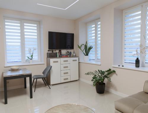 a white living room with a tv and a chair at Sodu apartment in Kaunas