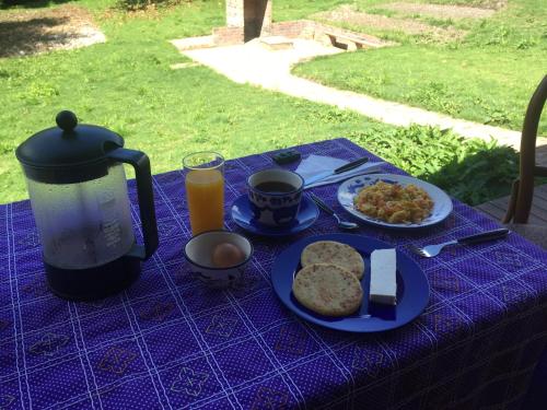 a blue table with a breakfast of eggs bread and toast at Titué Refugio , Cabañas in La Calera