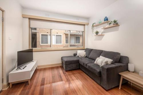 a living room with a couch and a window at Bright & Comfy 2 Bedroom St Kilda East Apartment in Melbourne
