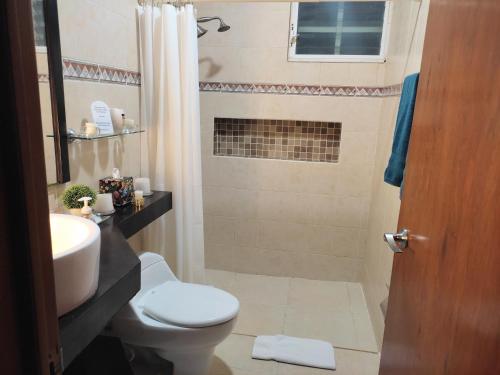 a bathroom with a toilet and a sink and a shower at Casa Cristal in Cancún