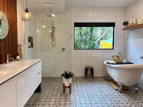 baño con bañera, 2 lavabos y ventana en Arthurs Seat Cottage - Sulla Collina en Arthurs Seat