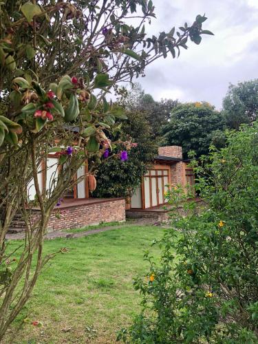 a house in a garden with a yard at Titué Refugio , Cabañas in La Calera