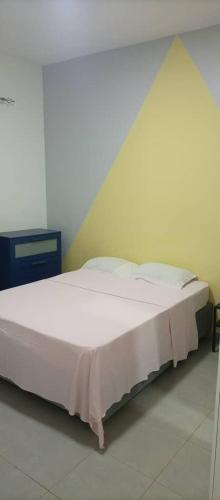 a white bed in a room with a yellow wall at Résidence Marie France MENDY in Toubab Dialaw