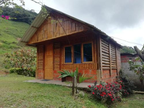 a small wooden cabin with flowers in front of it at Cabañas orquídea in Norcasia
