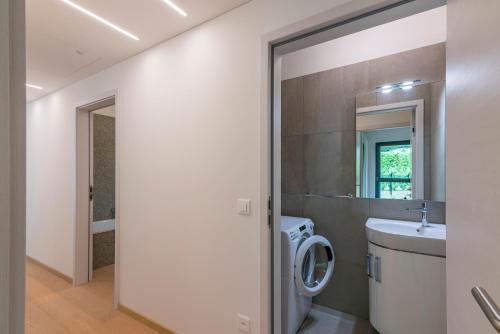 ein Badezimmer mit einer Waschmaschine und einem Waschbecken in der Unterkunft 7 - Gioiello Moderno a Montagnola in Collina d'Oro
