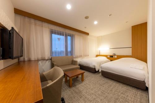 um quarto de hotel com duas camas e uma televisão em JR CLEMENT INN HIMEJI em Himeji