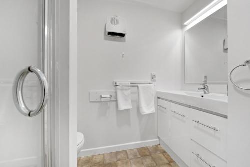 a white bathroom with a sink and a toilet at Central town apartment in Queenstown