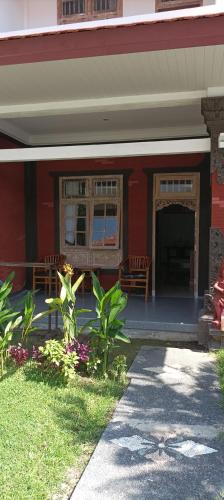 a red building with a porch with two benches at Hotel My New Lovina in Lovina