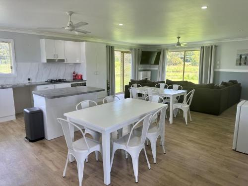 a kitchen and living room with white tables and chairs at Stoney Park Holiday Park in Telegraph Point