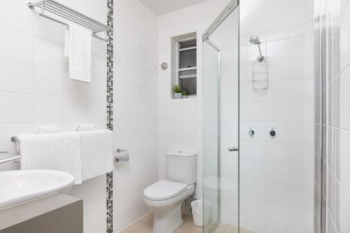 a white bathroom with a toilet and a shower at Waterview Airlie Beach in Airlie Beach