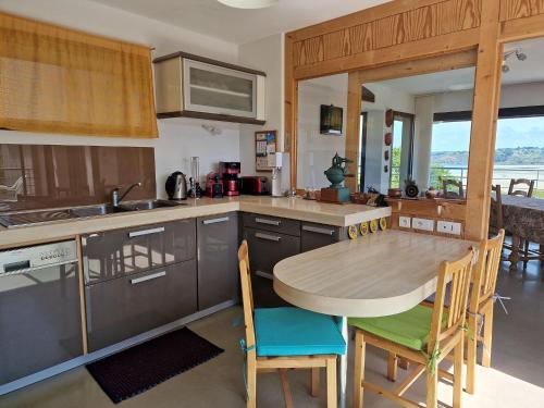 une cuisine avec une table et des chaises en bois, une table et un comptoir dans l'établissement Villa in Locquirec with Stunning Sea Views, à Locquirec