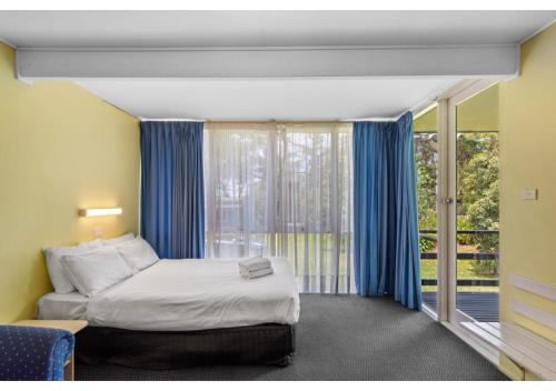 a bedroom with a bed and a large window at Discovery Parks - Burrill Lake, Ulladulla in Burrill Lake