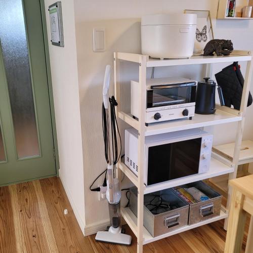 a kitchen shelving unit with a kitchen utensils at Biei Central Villa - Green Garden in Biei