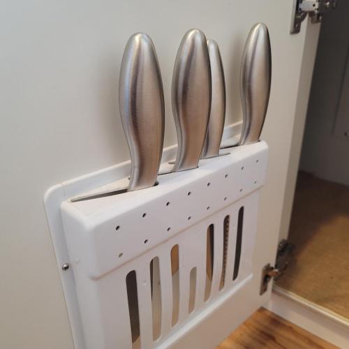 a white holder with four silver utensils in it at Biei Central Villa - Green Garden in Biei