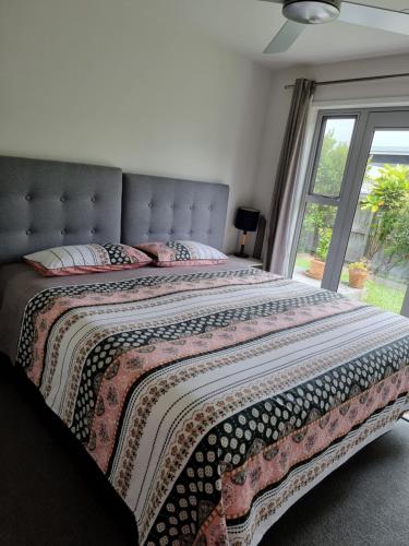 um quarto com uma cama grande e uma janela grande em Cosy Mangawhai House em Mangawhai