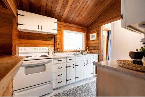 Il comprend une cuisine avec des appareils blancs et un plafond en bois. dans l'établissement Muskoka Ski Chalet, à Huntsville